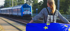 Junge Frau mit Europaflagge am Bahnhof